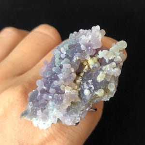 May include: A purple and white agate ring with a unique, bubbly texture. The ring is set in a silver band.