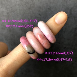 Pode incluir: Quatro an&eacute;is de pedra preciosa rosa de tamanhos diferentes, empilhados em um dedo. Os an&eacute;is s&atilde;o etiquetados com seus tamanhos em mil&iacute;metros e tamanhos de an&eacute;is portugueses: 01:16,9 mm (tamanho 14-15), 02:17,1 mm (tamanho 15), 03:17,1 mm (tamanho 15), 04:17,3 mm (tamanho 15-16).