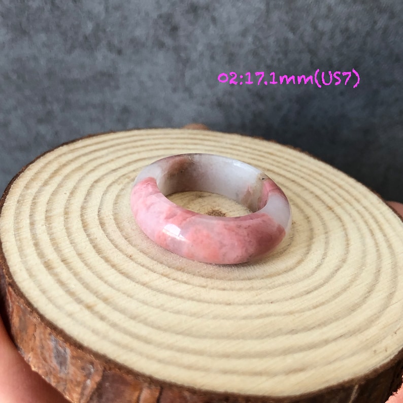 Pode incluir: Um anel de pedra polida de cor rosa e branca. O anel tem 17,1 mm de tamanho e est&aacute; etiquetado como US7.