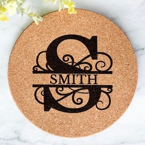 May include: A round cork trivet with a black engraved design of a large letter "S" with a decorative flourish and the word "SMITH" underneath.