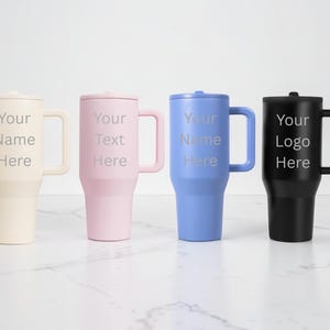 Puede incluir: Cuatro vasos aislados con asas y tapas en crema, rosa, azul y negro. Cada vaso tiene el texto "Your Name Here", "Your Text Here" o "Your Logo Here" en fuente plateada. Los vasos est&aacute;n sobre una superficie blanca.