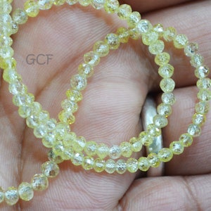 May include: A strand of yellow faceted gemstone beads. The beads are small and round, and they have a shiny, translucent finish.