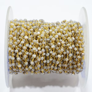 May include: A spool of gray gemstone beads with gold chain links. The beads are faceted and have a subtle shimmer.