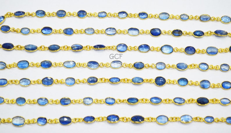 May include: A strand of blue kyanite gemstone beads with gold-toned metal connectors. The beads are oval-shaped and have a slightly iridescent finish. The strand is approximately 18 inches long.