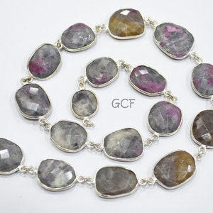Può includere: Una collana a catena d'argento con pietre preziose sfaccettate di forma ovale in tonalità di grigio, rosa e marrone. La collana è realizzata con maglie di catena d'argento e ha una chiusura a moschettone.