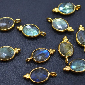 Puede incluir: Diez colgantes ovalados de color dorado con piedras preciosas de labradorita azul verdosa facetadas. Cada colgante tiene un pequeño bucle en la parte superior para sujetarlo a una cadena o cordón.