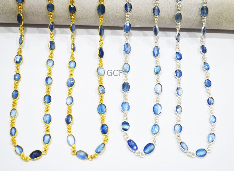 May include: Four strands of blue gemstone beads on a gold and silver chain. The beads are oval shaped and have a light blue color with a shimmery effect. The chains are delicate and have a polished finish.