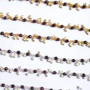 May include: Multiple strands of beaded chain featuring faceted dark purple stones and small white pearls. The chains are available in gold-toned and silver-toned metal finishes, with the beads arranged in a repeating pattern along the links.
