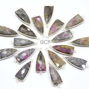 May include: A collection of 16 silver-toned pendant charms featuring a variety of pink and gray gemstone shapes. Each charm has two silver loops for attaching to jewelry.