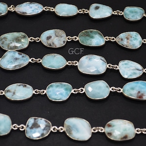 May include: A strand of light blue gemstone beads with silver connectors. The beads are oval shaped and have a cloudy, marbled appearance.
