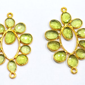 May include: Two gold-tone metal earring pendants with a delicate, leafy design. Each pendant features a cluster of light green faceted stones.
