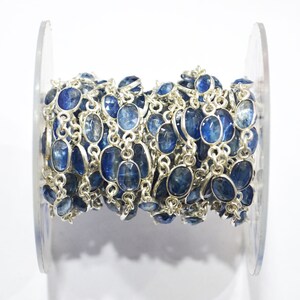 May include: A silver chain with blue gemstone beads. The chain is wound around a clear plastic spool.