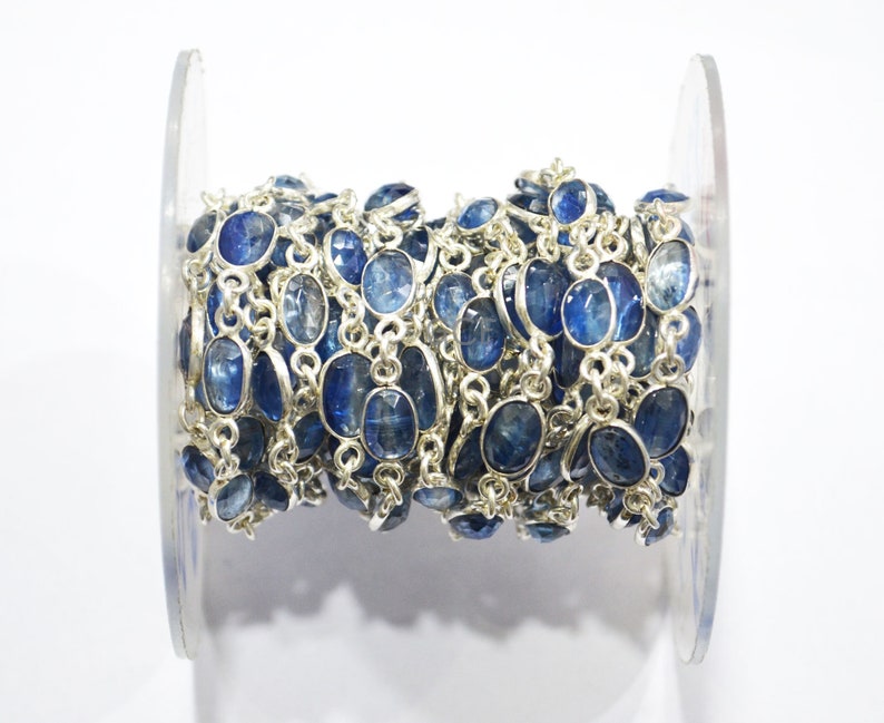 May include: A silver chain with blue gemstone beads. The chain is wound around a clear plastic spool.