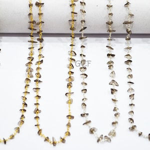 Puede incluir: Cinco hebras de cuentas de piedras preciosas marrones enhebradas en una cadena de oro. Las cuentas tienen una forma irregular y un aspecto natural y crudo.