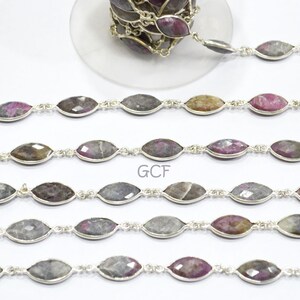May include: A silver chain with faceted, oval-shaped gemstone beads in shades of grey, pink, and brown. The chain is approximately 18 inches long and is ideal for jewellery making.