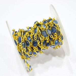 May include: A gold chain with blue gemstone beads. The chain is coiled on a white spool.