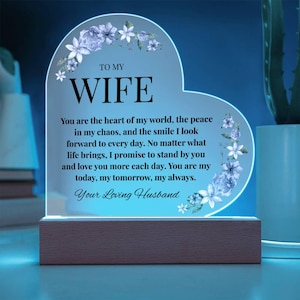 May include: Heart-shaped LED night light with the text "TO MY WIFE" and a loving message. Features floral accents and a wooden base. A romantic gift.