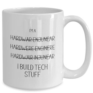May include: White ceramic coffee mug with black text that reads "I'm a Hardwar Enjunear Hardwere Enginere Hardwair Injunear I Build Tech Stuff".