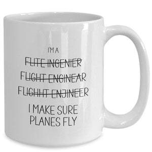 May include: White ceramic mug with a curved handle. The mug has black text that reads "I'M A FLITE INGENIER, FLIGHT ENGINEAR, FLIGHT ENGINEER, I MAKE SURE PLANES FLY."
