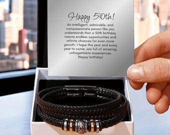 May include: A black leather bracelet with a silver and gold charm. The bracelet is in a white box with a card that reads "Happy 50th! An intelligent, admirable, and compassionate person like you understands that a 50th birthday means endless opportunities and infinite chances for even more growth. I hope this year and every year to come, are full of amazing, unforgettable experiences. Happy birthday!"