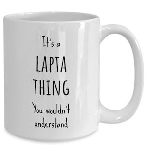 May include: White ceramic coffee mug with black text that reads "It's a LAPTA THING You wouldn't understand".