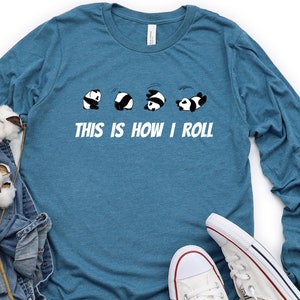 May include: A teal blue long-sleeved t-shirt with a graphic of five pandas rolling down a hill. The text "This is how I roll" is printed below the pandas.