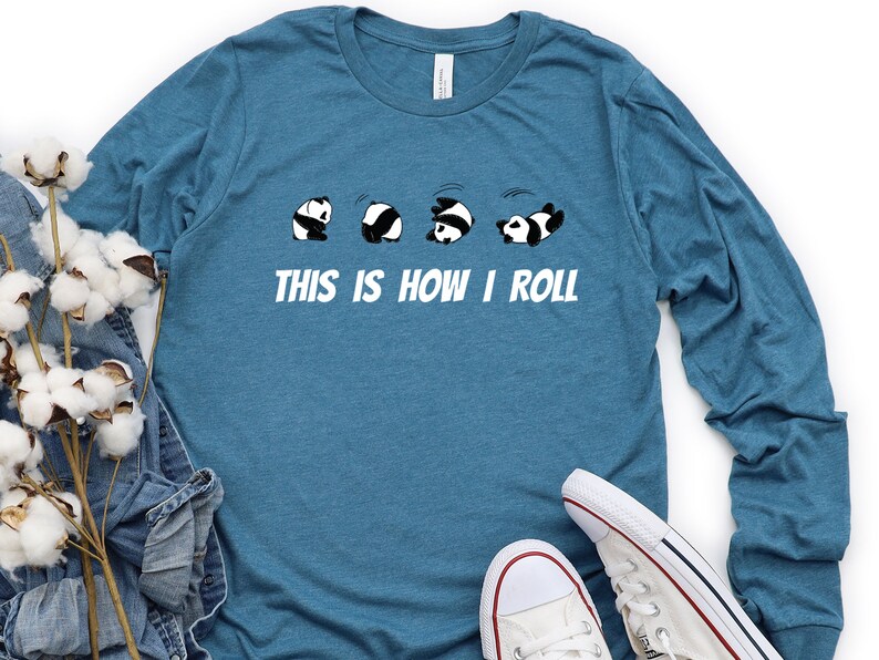 May include: A teal blue long-sleeved t-shirt with a graphic of five pandas rolling down a hill. The text "This is how I roll" is printed below the pandas.
