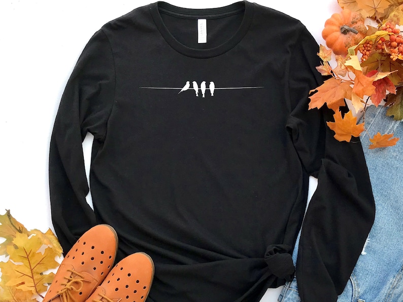 May include: Black long-sleeve t-shirt with a white silhouette of four birds on a wire.