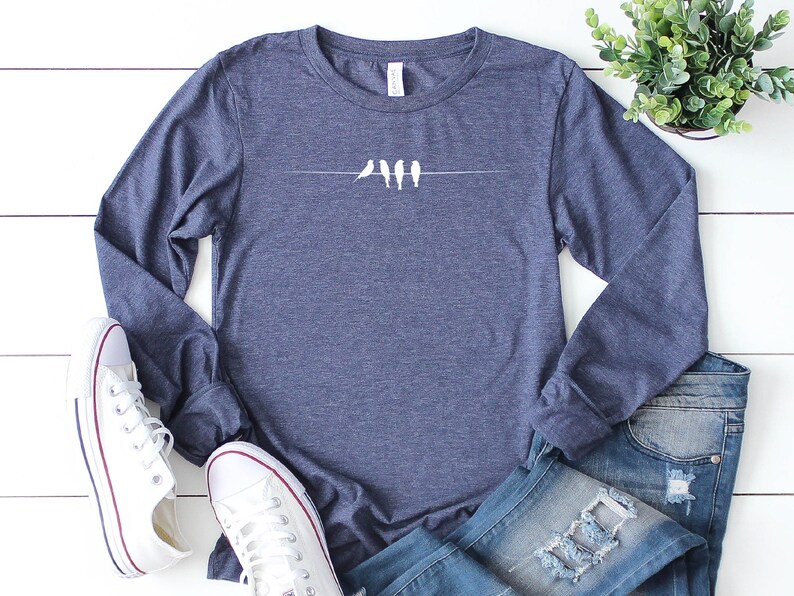 May include: A navy blue long-sleeved shirt with a white graphic of five birds perched on a wire.