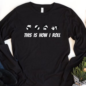 May include: Black long-sleeve shirt with a graphic of five panda bears rolling down a hill. The text "This is how I roll" is printed below the panda bears.