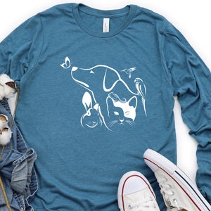 Op de afbeelding: Een tealblauw longsleeve t-shirt met een witte afbeelding van een hond, een kat, een konijn en twee vogels. De afbeelding is gecentreerd op het shirt.