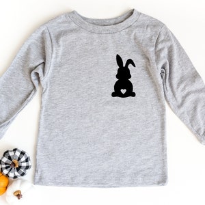 May include: A gray long-sleeved shirt with a black silhouette of a bunny with a small white heart on its chest.