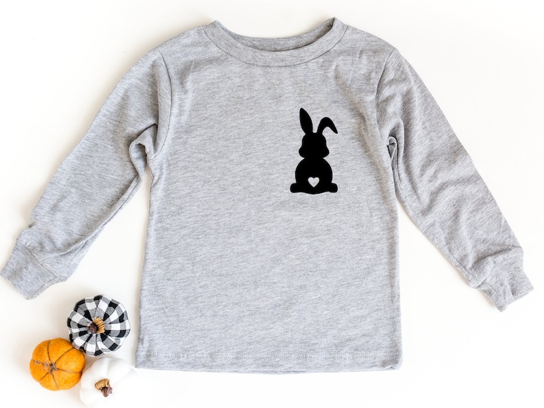 May include: A gray long-sleeved shirt with a black silhouette of a bunny with a small white heart on its chest.
