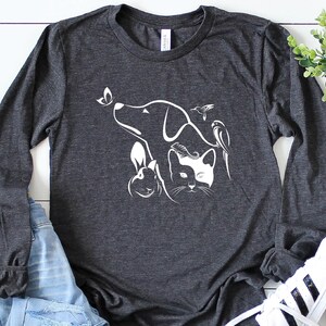 Op de afbeelding: Een donkergrijs longsleeve t-shirt met een wit silhouetontwerp van een hond, kat, konijn, vlinder en kolibrie.