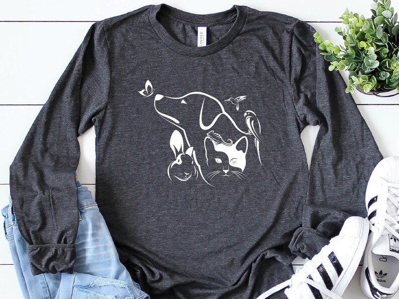 Op de afbeelding: Een donkergrijs longsleeve t-shirt met een wit silhouetontwerp van een hond, kat, konijn, vlinder en kolibrie.