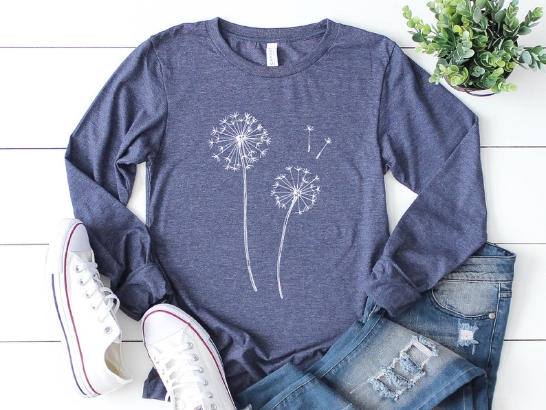 May include: A navy blue long-sleeved t-shirt with a white dandelion graphic. The shirt is made of a soft, comfortable material.