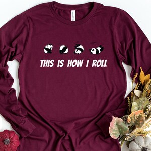 May include: A maroon long-sleeved t-shirt with a graphic of five pandas rolling. The text "This is how I roll" is printed below the pandas.