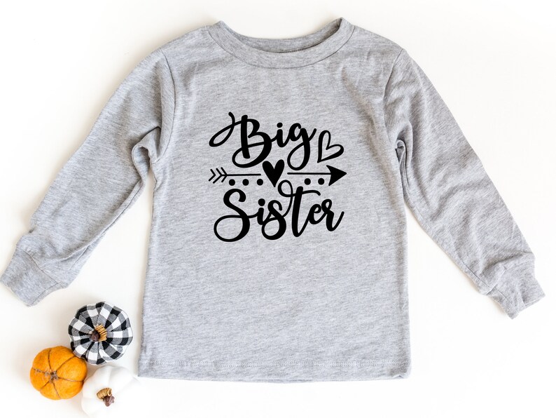 May include: Gray long-sleeve shirt with black text that reads "Big Sister" with an arrow and hearts.