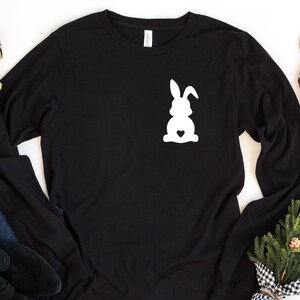 May include: Black long-sleeved shirt with a white silhouette of a bunny rabbit with a heart on its chest.