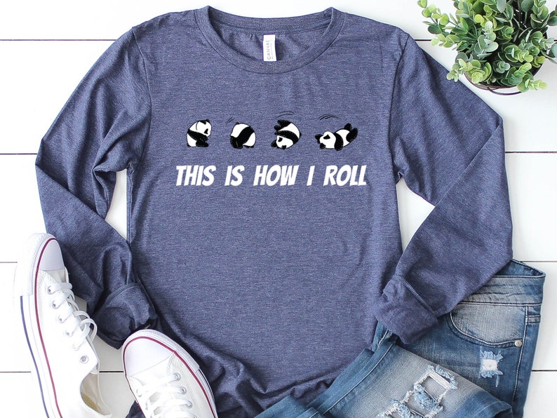 May include: A navy blue long-sleeved t-shirt with a graphic of five pandas rolling down a hill. The text "This is how I roll" is printed below the pandas.