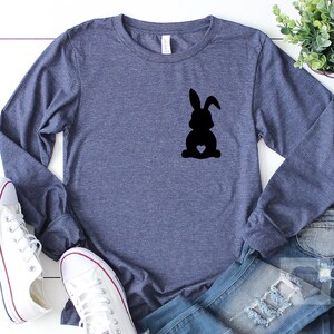 May include: A navy blue long-sleeved shirt with a black silhouette of a rabbit with a heart on its chest.