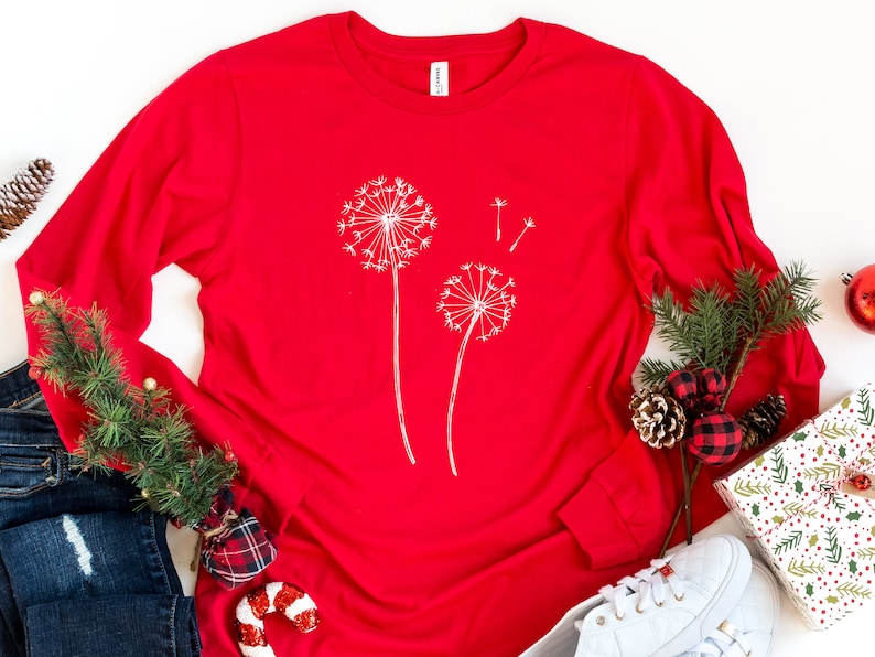 May include: Red long-sleeved t-shirt with a white dandelion design.