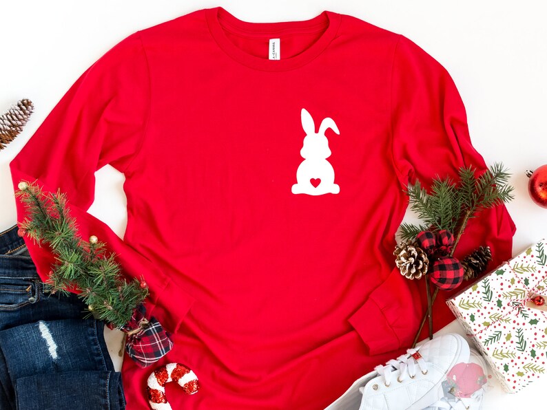 May include: Red long-sleeved shirt with a white silhouette of a bunny rabbit with a heart in its chest.