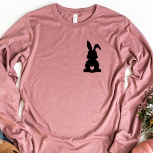 May include: A long-sleeved, mauve t-shirt with a black silhouette of a bunny rabbit with a heart on its chest.