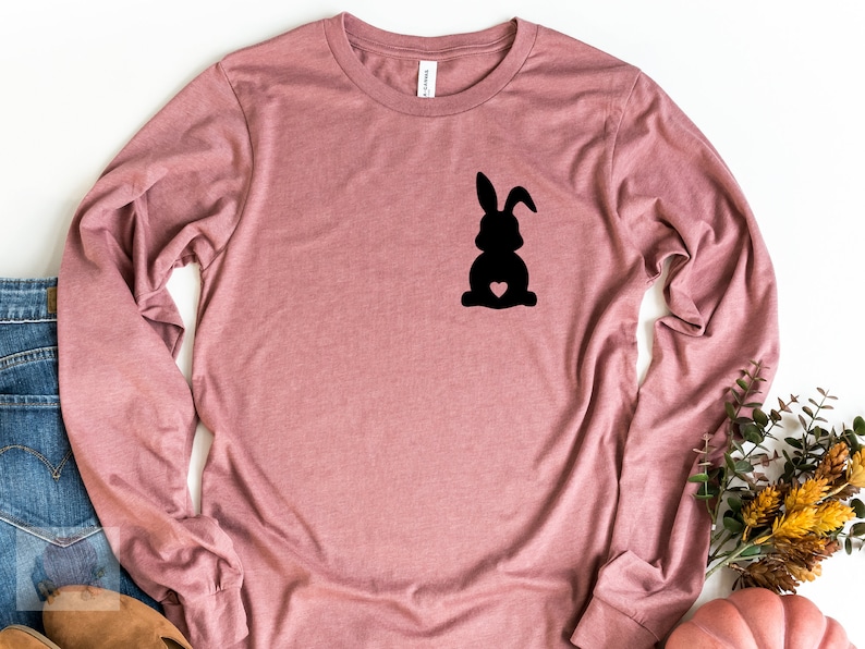 May include: A long-sleeved, mauve t-shirt with a black silhouette of a bunny rabbit with a heart on its chest.