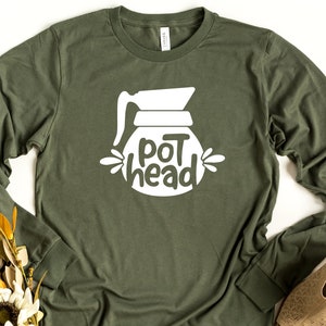 May include: A green long-sleeved t-shirt with a white graphic of a coffee pot and the text "pot head".