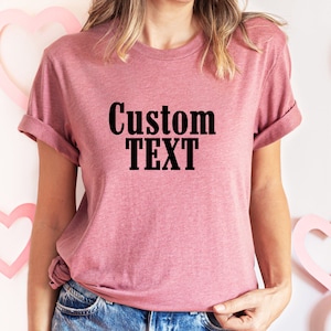 May include: A pink t-shirt with the text "Custom Text" printed in black.