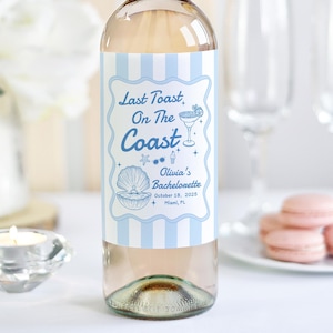 May include: A blue and white striped wine bottle label with the text "Last Toast, On The Coast" and a seashell design. The label also includes the text "Olivia's Bachelorette" and the date "October 10, 2005".