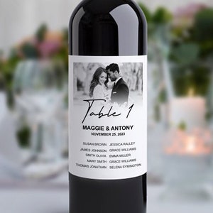 Könnte beinhalten: Ein Weinetikett mit einem Schwarzweißfoto eines Hochzeitspaares. Das Etikett enthält auch den Text "Tisch 1", "Maggie & Antony", "25. November 2023" und eine Namensliste.