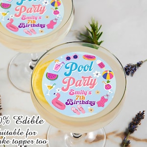 May include: Two clear cocktail glasses with a slice of lemon and a circular edible topper that reads "Pool Party, Smily's 7th Birthday." The toppers feature illustrations of a flamingo, watermelon, and other pool-themed icons. The text "100% Edible" is also visible.